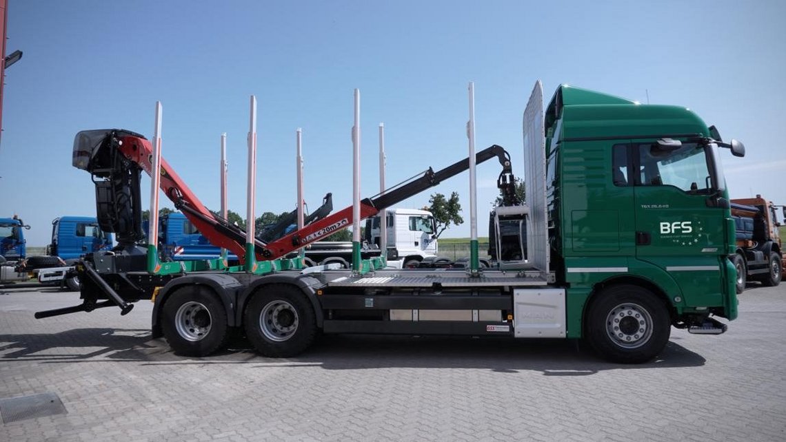 grüner MAN Holztransporter mit Palfinger Ladekran